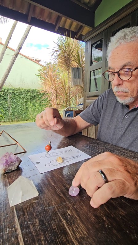 Professor Walter Nieblas usando pêndulo sobre um gráfico radiônico para alinhar os chakras